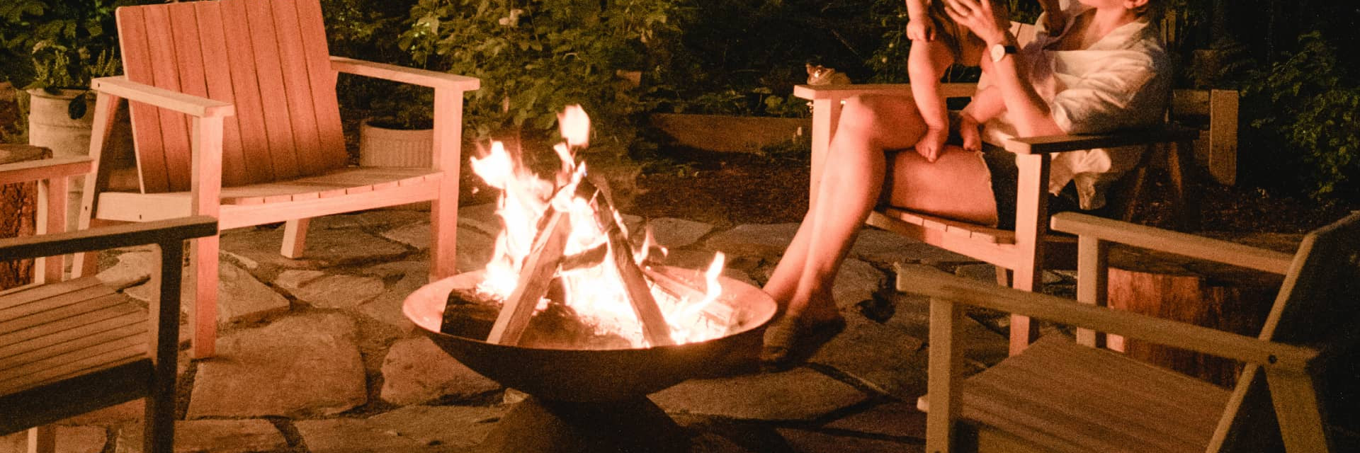 Neighbor outdoor fire pit surrounded by teak adirondack chairs
