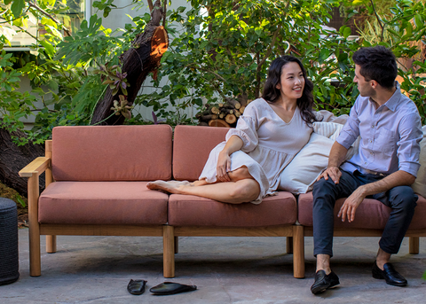 Couple on a three seater outdoor teak sofa