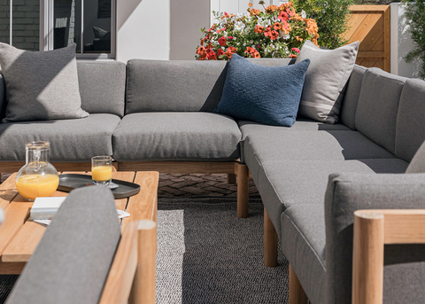 Neighbor outdoor sectional in grey with throw cushions and a teak coffee table