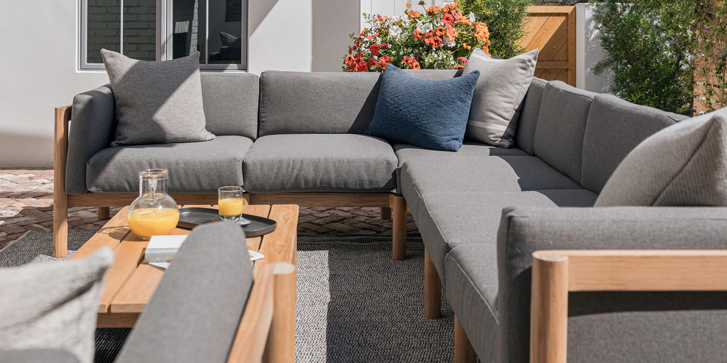 Neighbor outdoor sectional in grey with throw cushions and a teak coffee table