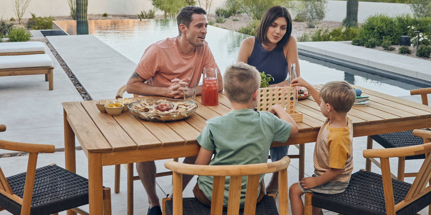 Young family eating outside on a six seater teak dining table and chairs