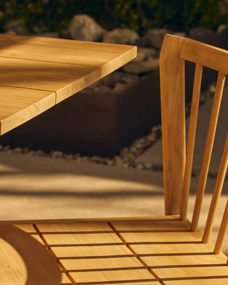 Teak outdoor dining chair next to teak dining table