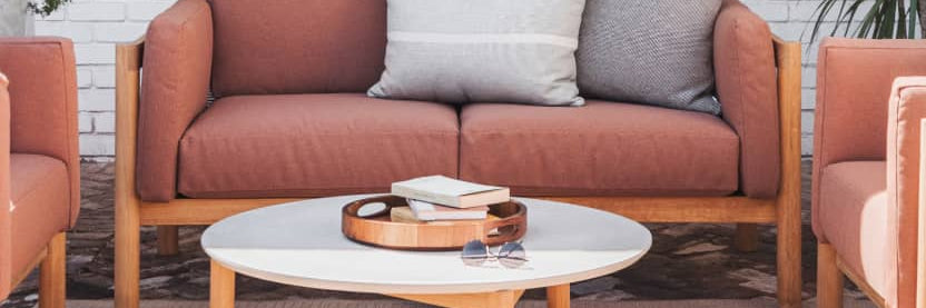 Rust colored upholstered loveseat with plush throw pillows 