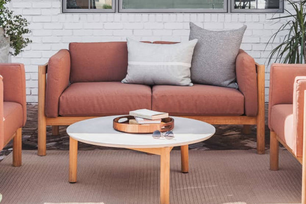 Rust colored upholstered loveseat with plush throw pillows 