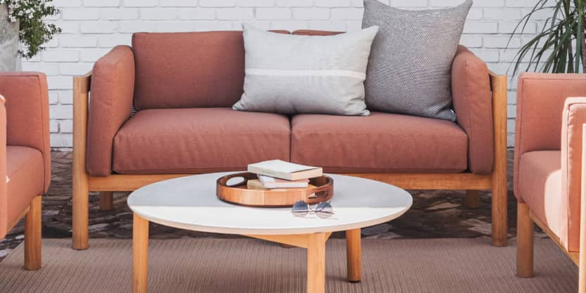 Rust colored upholstered loveseat with plush throw pillows 