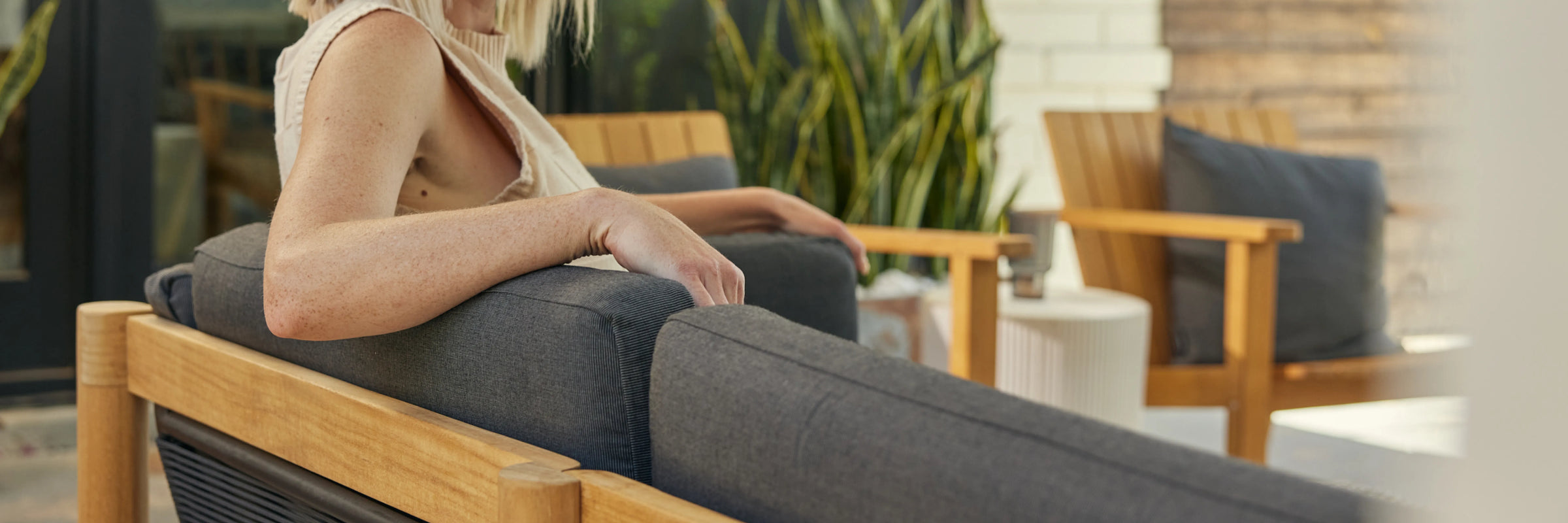 Closeup of Neighbor Haven Loveseat charcoal fabric cushion and teak frame in outdoor setting