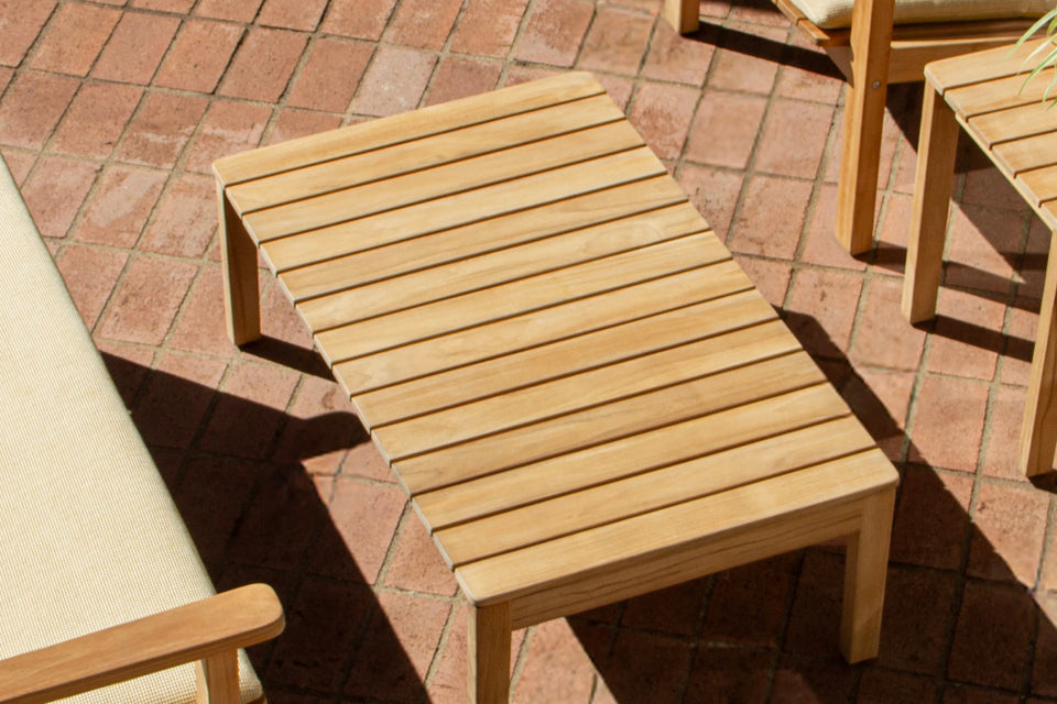 Overhead view of Neighbor Low Bench Pad with cream cushion on teak bench, matching chairs on terracotta tile patio
