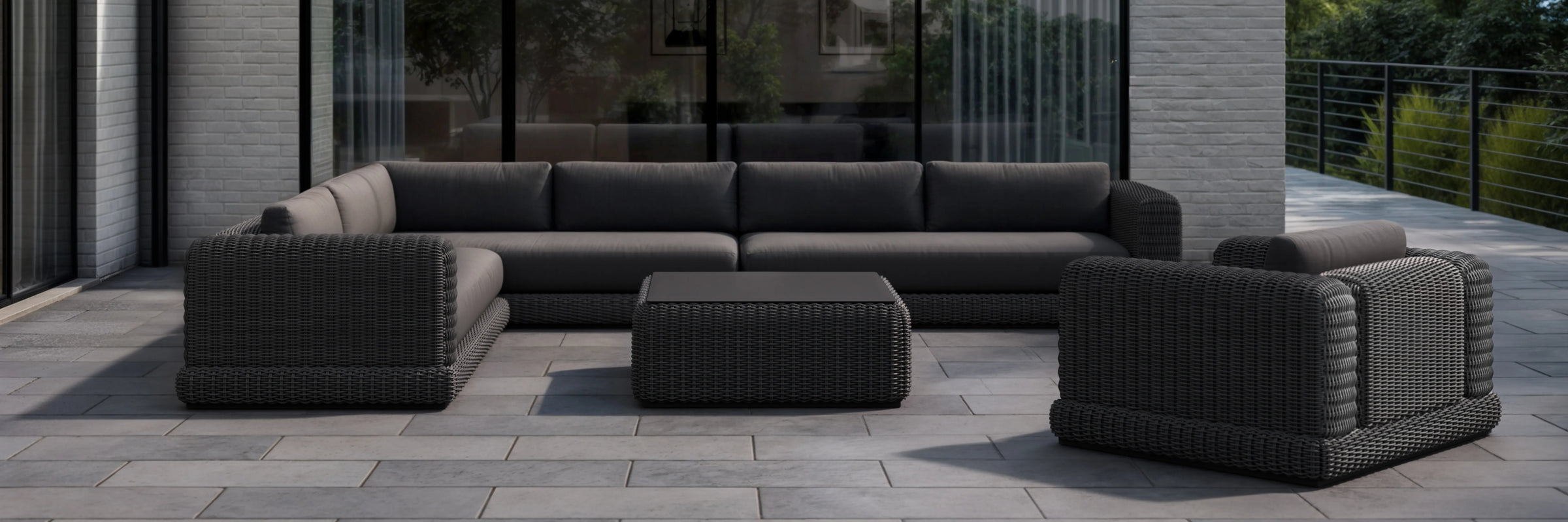 Neighbor Roundabout Sectional with Side Table in dark wicker and charcoal cushions on a paved patio with greenery