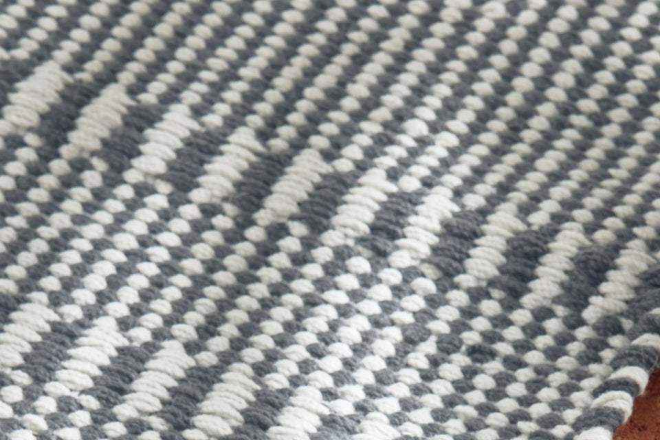 Neighbor Field Outdoor Rug with tonal woven pattern on an outdoor patio surface, partial lifestyle view