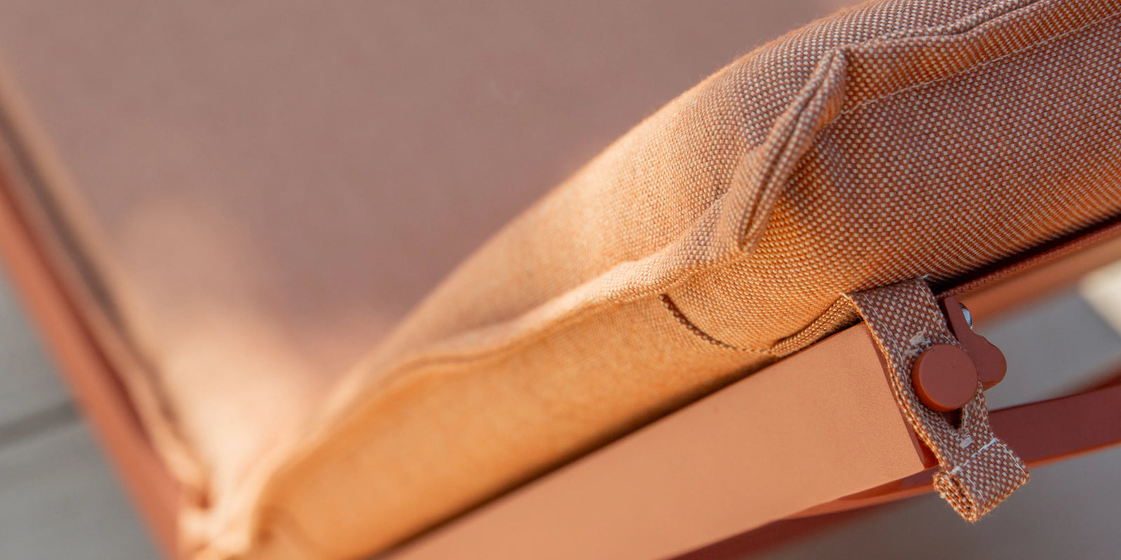 Closeup of Neighbor Terra Sun Lounger cream cushion and teak frame detail in outdoor light