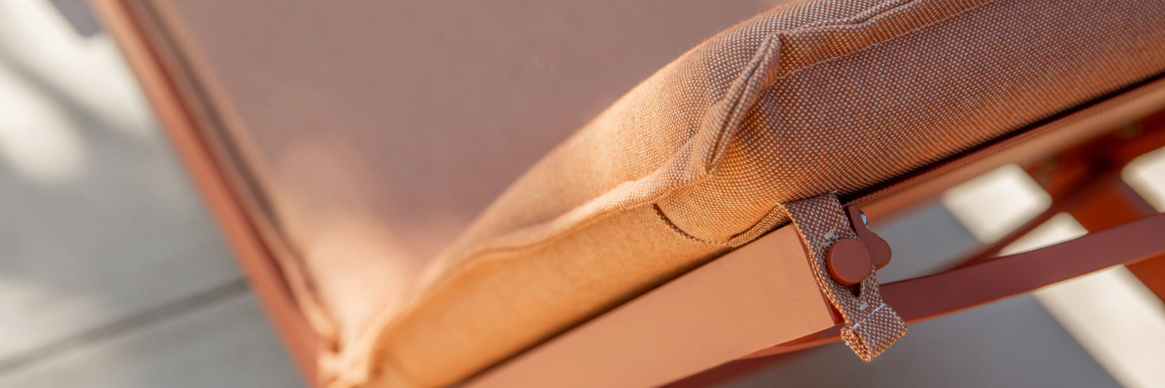 Closeup of Neighbor Terra Sun Lounger cream cushion and teak frame detail in outdoor light