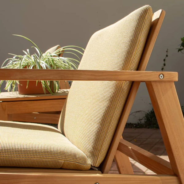 Low Lounge Chair with yellow woven grid-pattern cushions and teak frame on a terracotta tile patio, 3/4 front view