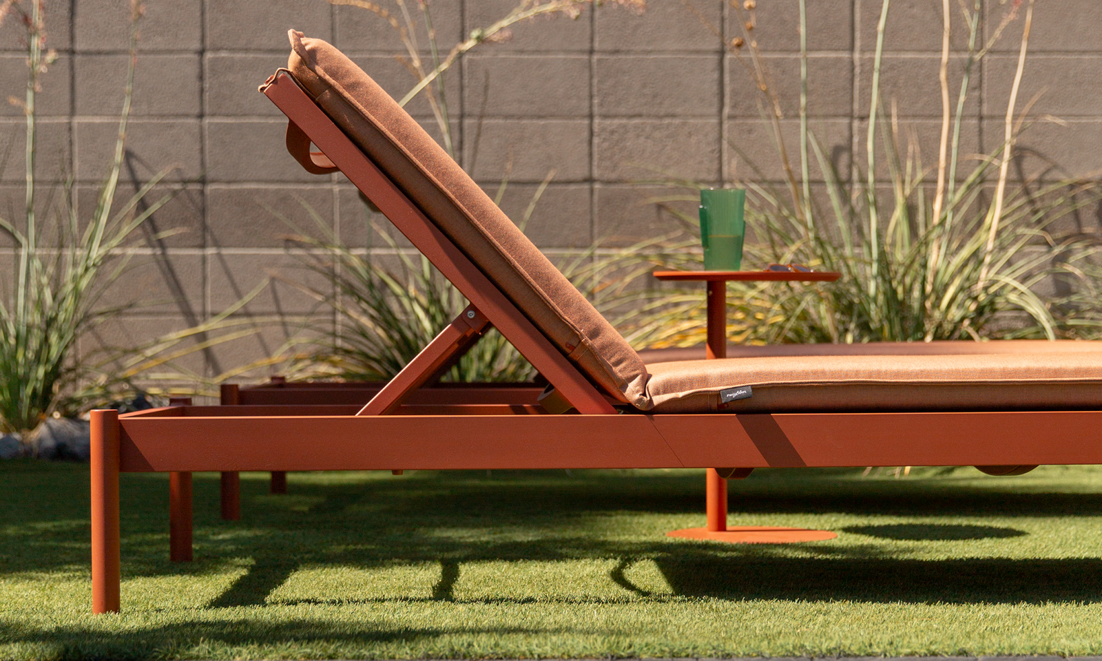 Aluminum sun lounger in terracotta finish with matching terracotta cushion and integrated side table on a lawn patio — Aluminum Outdoor Furniture collection