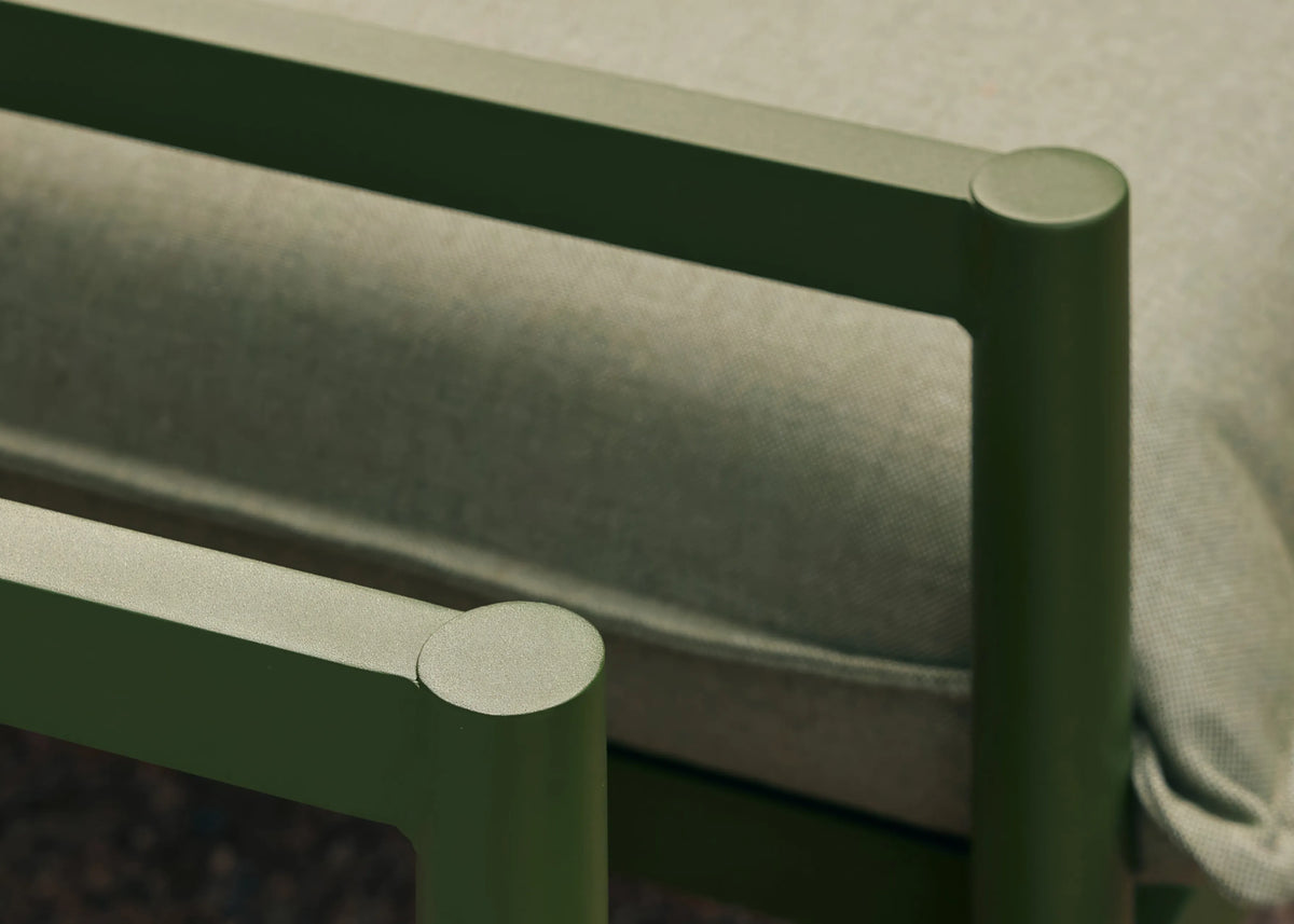 Close-up detail of a forest green powder-coated aluminum sofa frame corner with sage-colored cushion