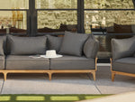 Neighbor Bluff Loveseat in charcoal upholstery with wood frame on concrete patio, large windows
