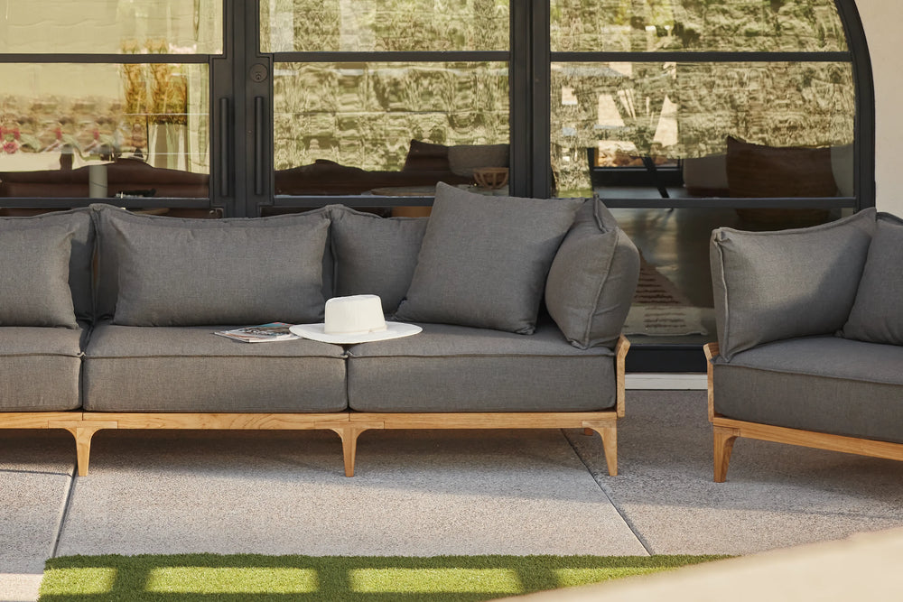 Neighbor Bluff Loveseat in charcoal upholstery with wood frame on concrete patio, large windows