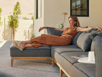 Woman on Neighbor Bluff Chaise Sectional in gray fabric with wood base on sunny patio