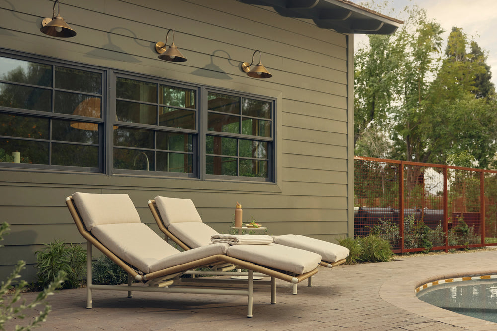 Two Neighbor Camber Chaise Lounges with cream cushions and woven cord backs reclined on a brick paver patio beside a sunken hot tub.
