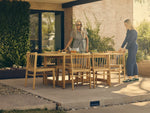 Neighbor Felloe Dining Set with natural wood round table and vertical slat chairs on concrete patio with garden.