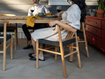 Two people seated at Neighbor Haven Dining Chairs with white cushions and teak frames at dining table indoors, modern decor visible