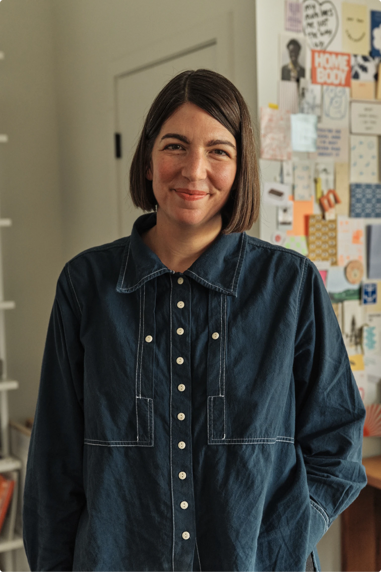 Portrait of Amanda Jane Jones in a denim shirt, standing in front of a colorful mood board