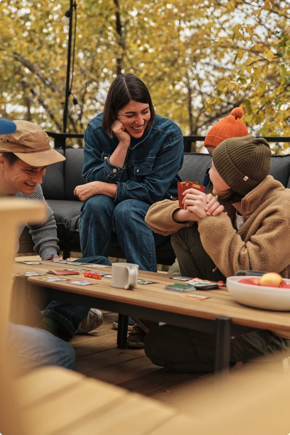 Amanda Jones laughs with her family while playing cards on the outdoor sectional, surrounded by autumn foliage