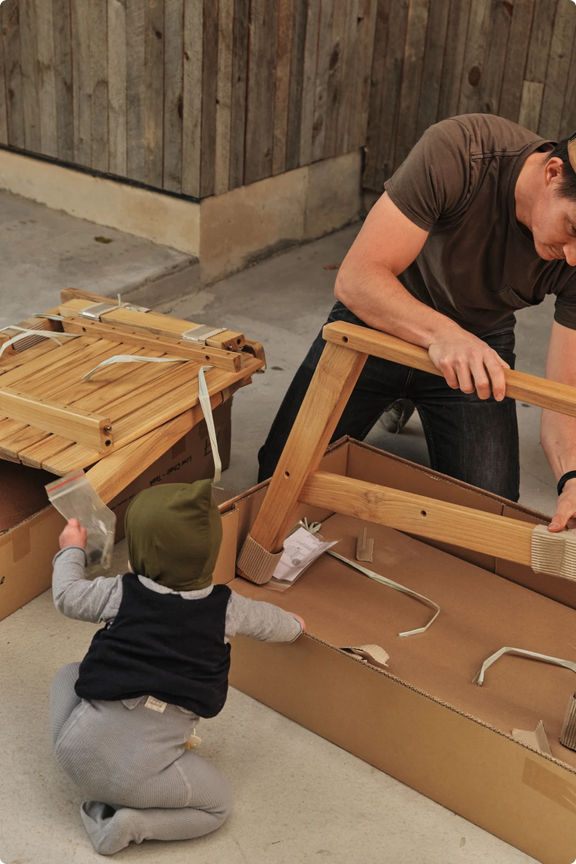 A child helping assemble outdoor furniture alongside an adult
