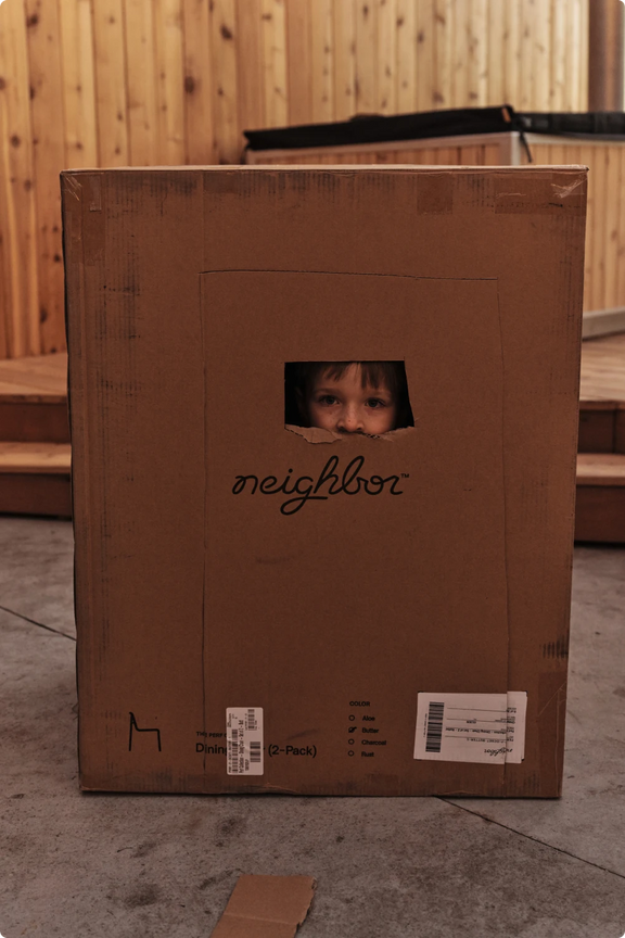 A cardboard box fort under construction on a concrete patio
