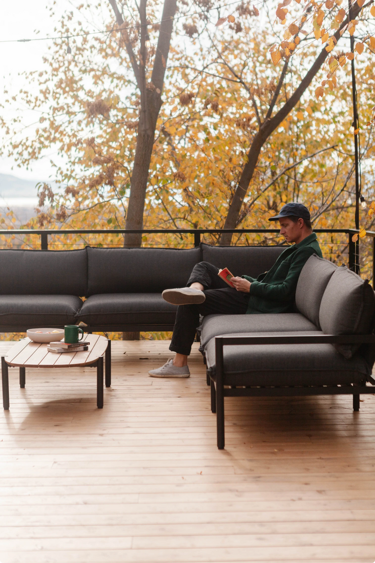 Cree Jones sitting on an outdoor sofa on the deck, surrounded by autumn foliage