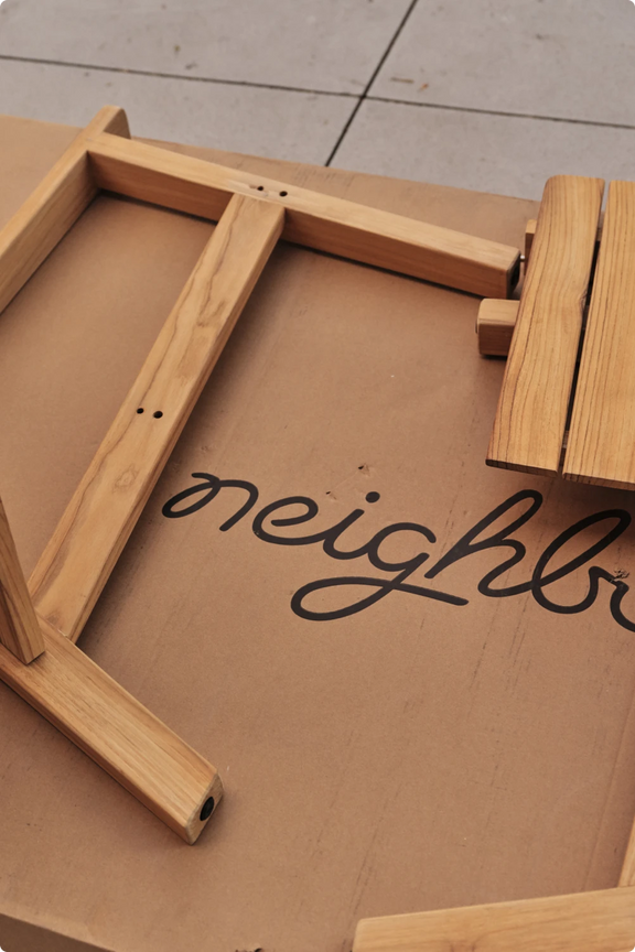 A child peeking out through a cutout window in a Neighbor branded box