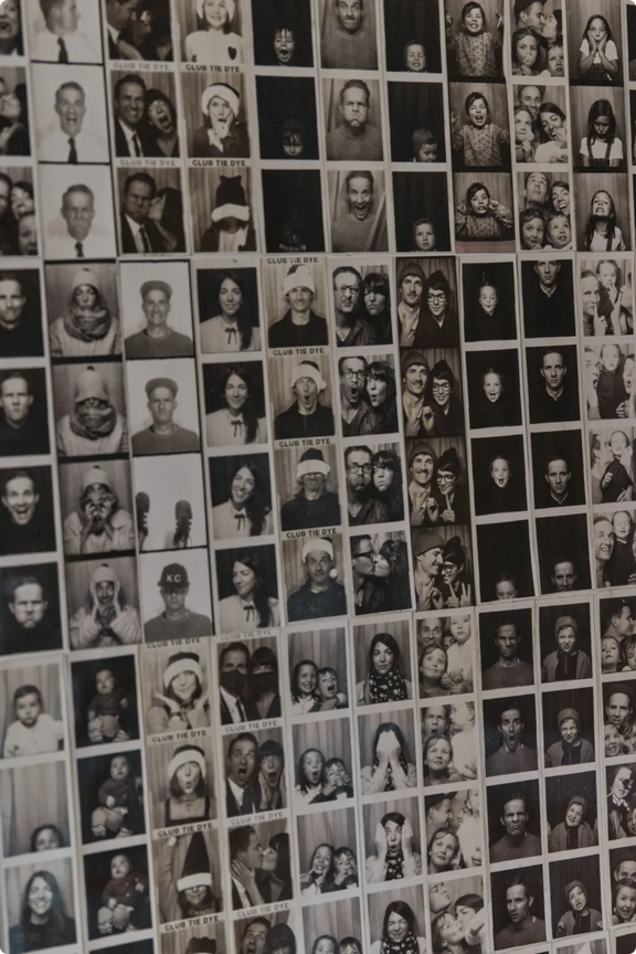 A wall covered in rows of vintage black-and-white photobooth strips featuring family and friends