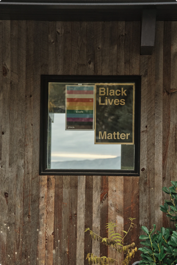 A framed Black Lives Matter poster and prints displayed on a wood-paneled wall