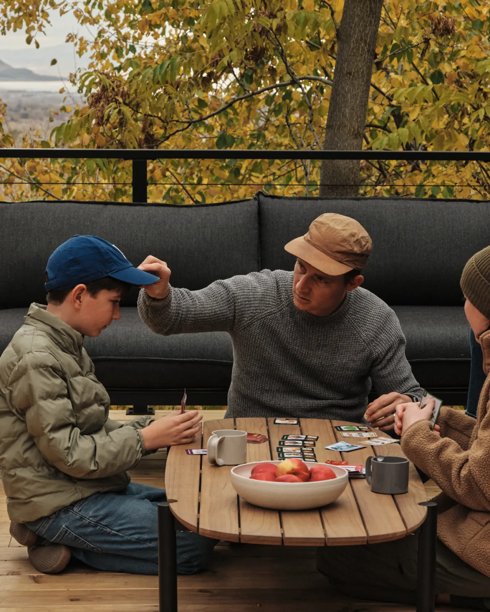 Family gathered on deck around Neighbor Terra Sectional during sunset over the Wasatch Mountains outside Provo, Utah