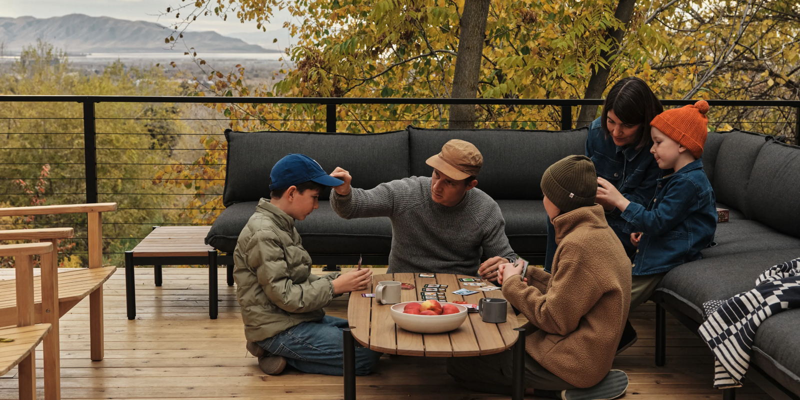 Family gathered on deck around Neighbor Terra Sectional during sunset over the Wasatch Mountains outside Provo, Utah