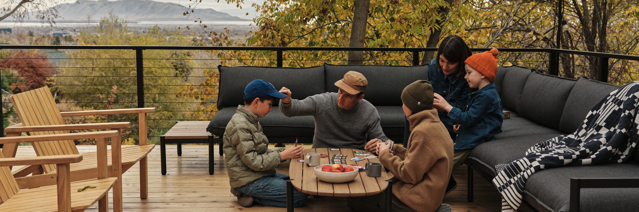 Family gathered on deck around Neighbor Terra Sectional during sunset over the Wasatch Mountains outside Provo, Utah