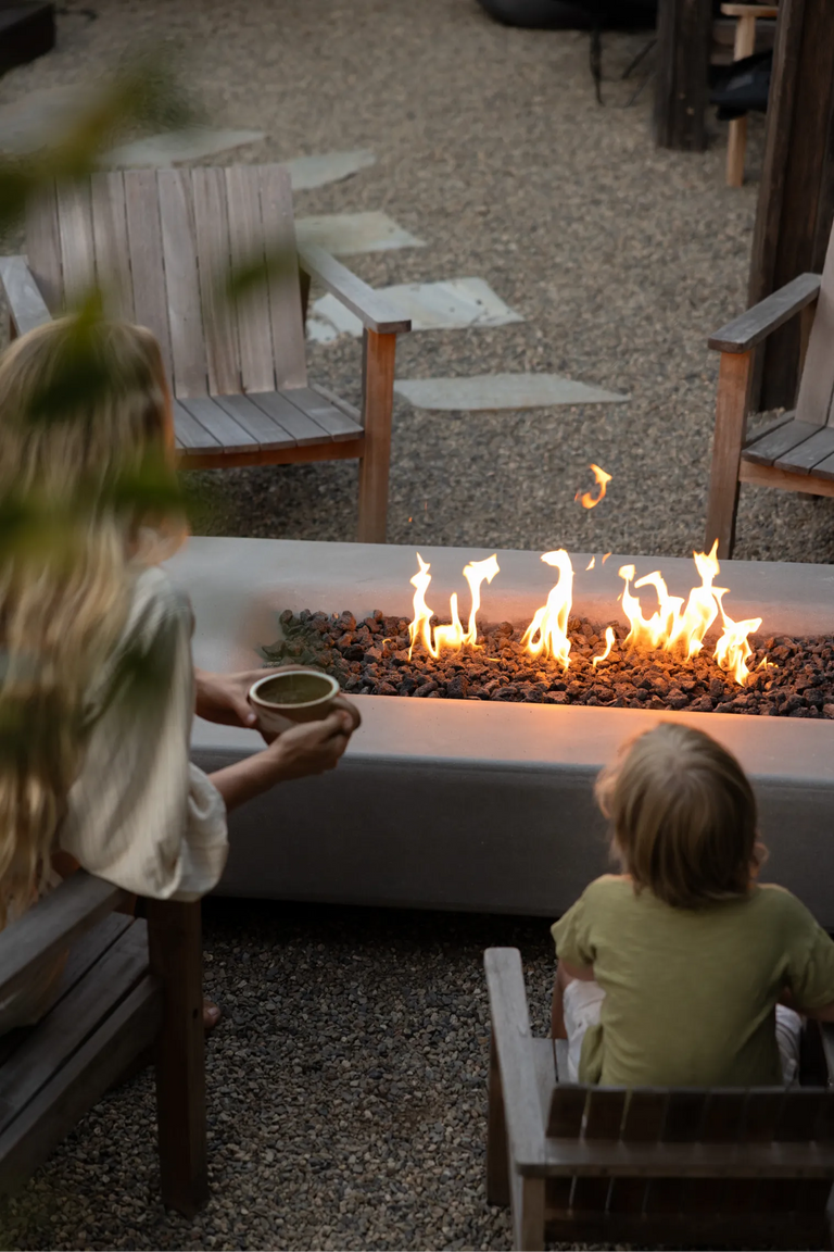 Taylr Anne Castro holds a mug while sitting near the fire table with her son in front of her