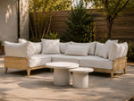 Neighbor Ped Side Table Short in Bone nested with the Ped Coffee Table before a teak sectional on a concrete patio