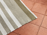 Neighbor Dune Rug in Basil with horizontal stripes in sage and white on terracotta tile patio surface
