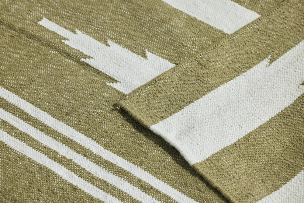 Neighbor Mesa Rug in Basil, detail showing olive green and cream striped geometric woven pattern with fold