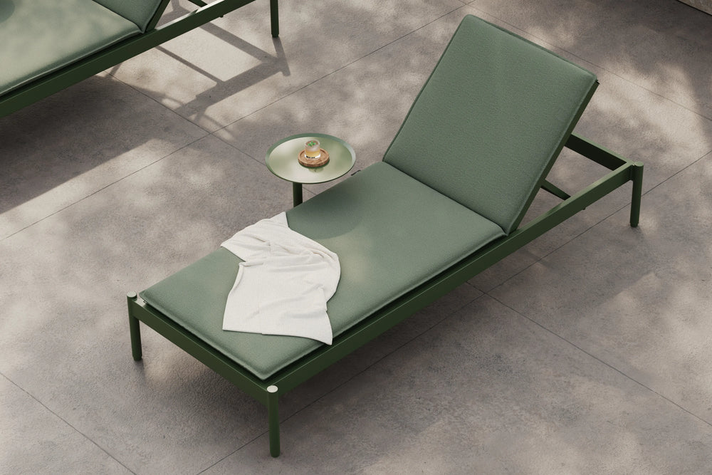 Neighbor Terra Sun Lounger in Charcoal with Putty cushions, modern reclining chaise on concrete patio with drink table