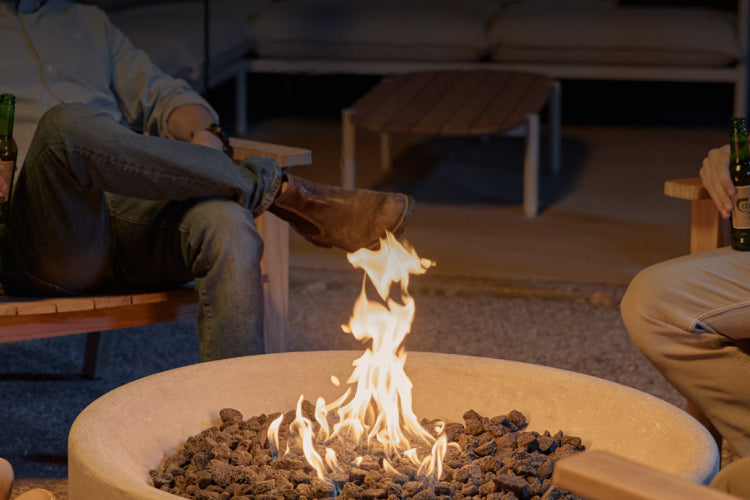 People gathered around a fire pit table with flames in a dimly lit patio