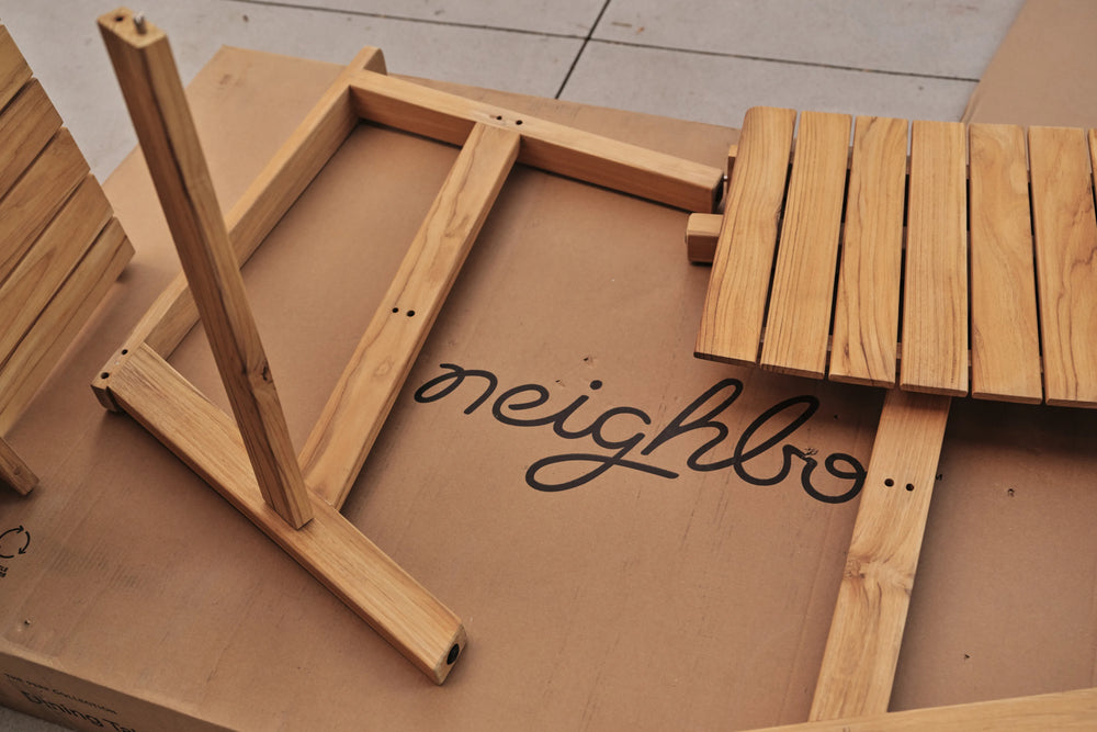 Hands inspecting wooden furniture components with Neighbor branding visible, quality control or assembly closeup