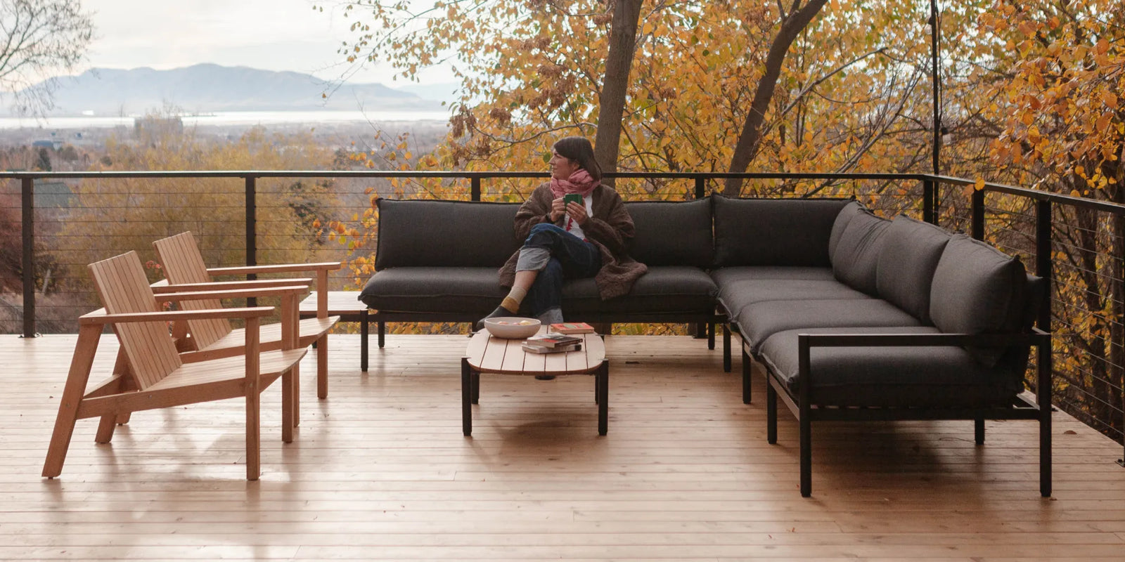 Amanda Jane Jones sitting on a Neighbor Terra Sectional outside on a wooden deck. 