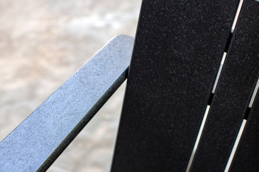 Close-up detail of Neighbor Low Chair arm and back in matte black recycled polywood slatted construction