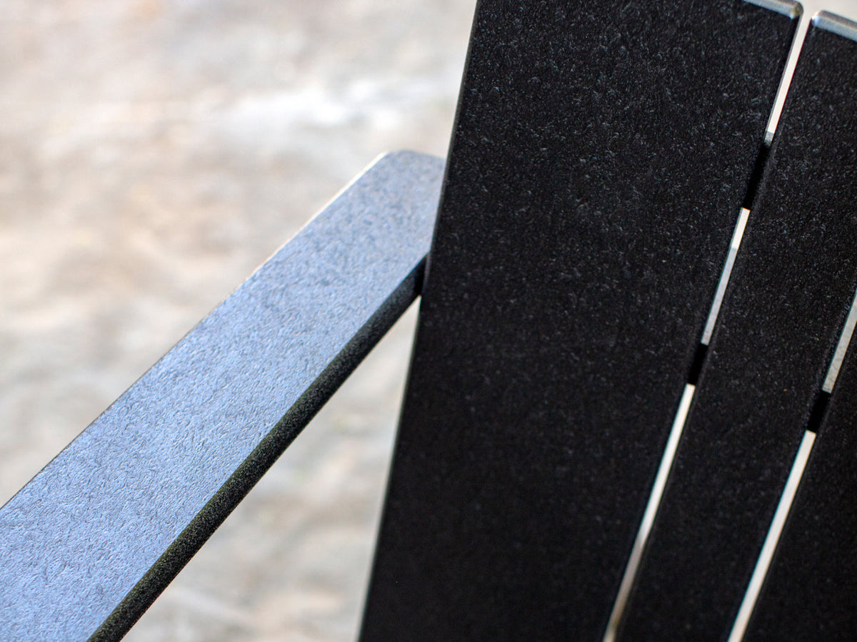 Close-up detail of Neighbor Low Chair arm and back in matte black recycled polywood slatted construction
