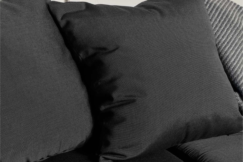 Close-up of deep charcoal outdoor cushions with wicker chair back visible, showing all-weather fabric texture