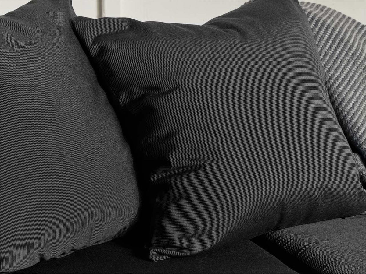 Close-up of deep charcoal outdoor cushions with wicker chair back visible, showing all-weather fabric texture