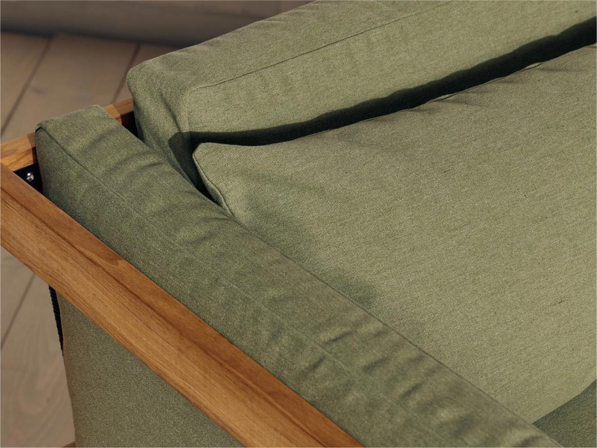 Overhead close-up of sage green Neighbor outdoor sofa cushion fitting into a teak frame corner