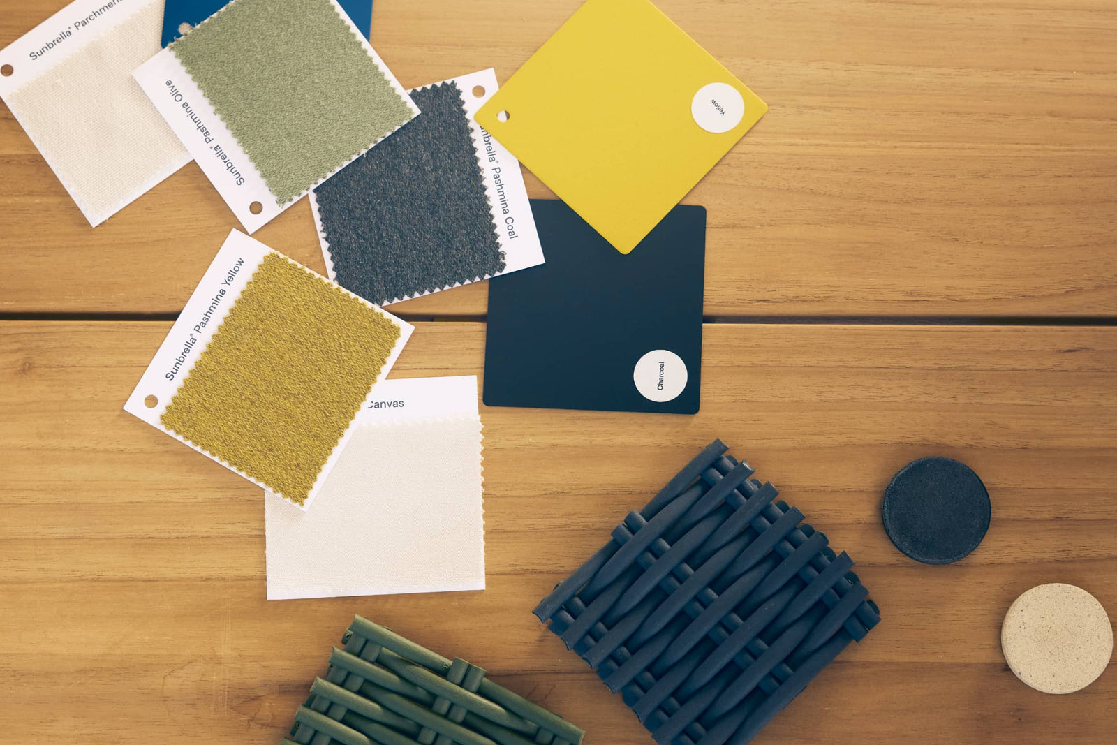Flat lay of Neighbor material and color swatches on teak - Sunbrella fabrics, polywood tiles, wicker cord, and concrete discs