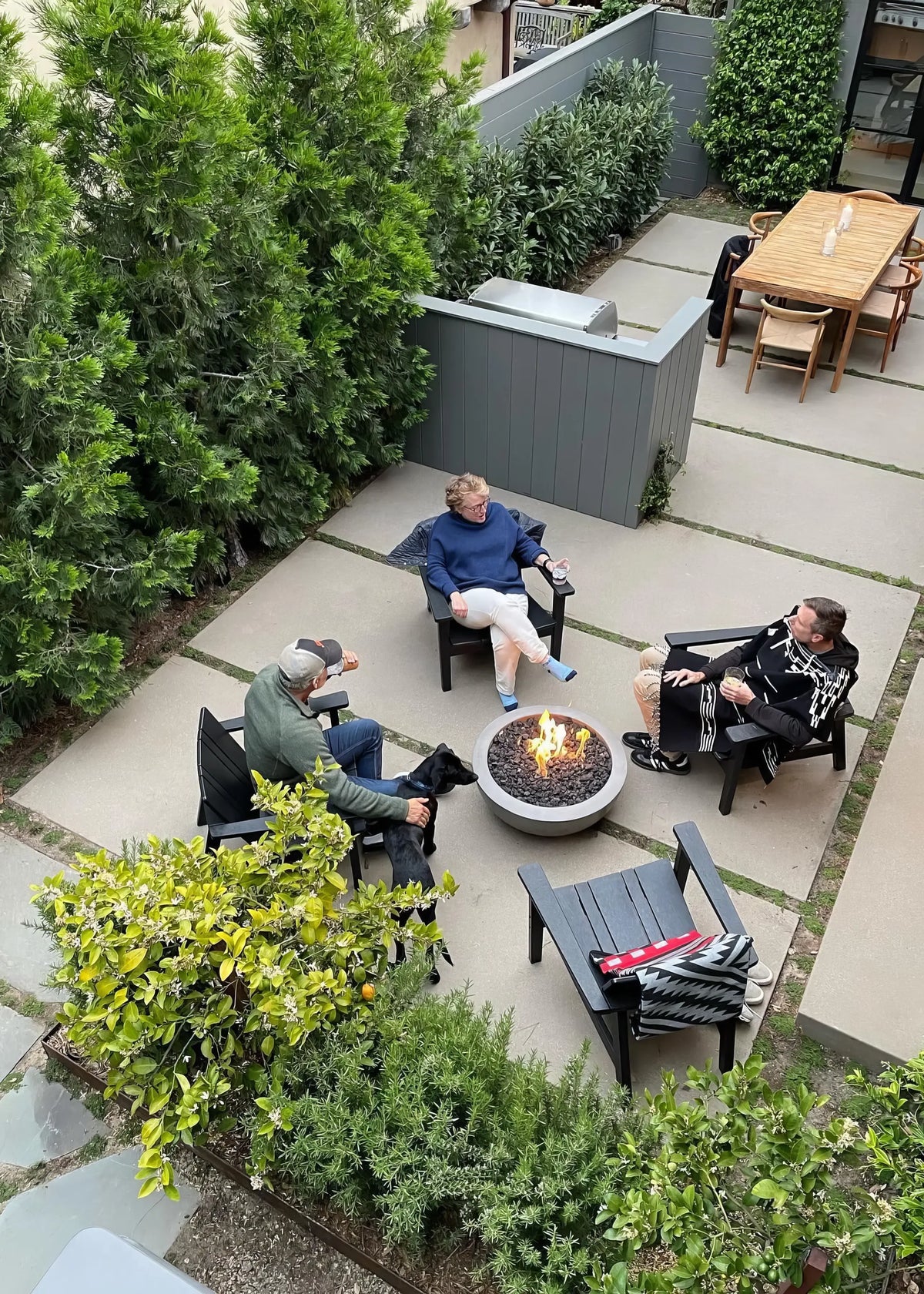 Overhead view of garden patio with charcoal outdoor chairs, fire table, and lush green landscaping